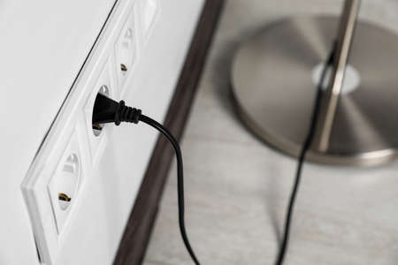 Floor lamp plugged into wall power socket indoors, closeup. Space for textの写真素材
