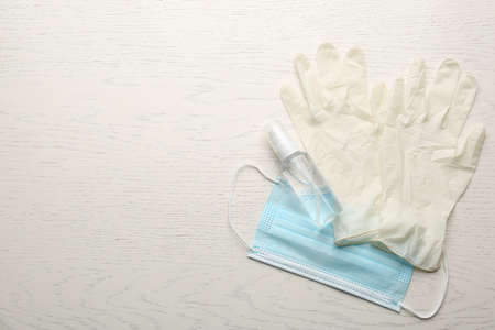 Medical gloves, protective mask and hand sanitizer on white wooden background, flat lay. Space for textの写真素材