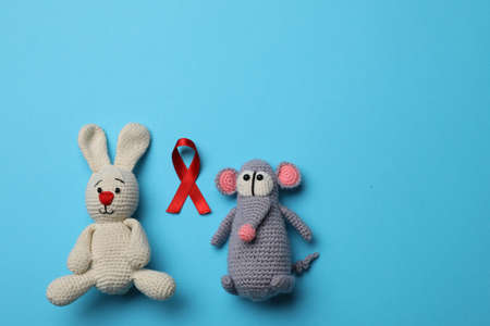 Cute knitted toys and red ribbon on blue background, flat lay with space for text. AIDS disease awarenessの写真素材