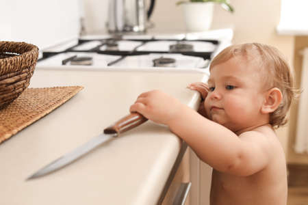 Little child holding a sharp knife in the kitchen. Dangerous situationの写真素材