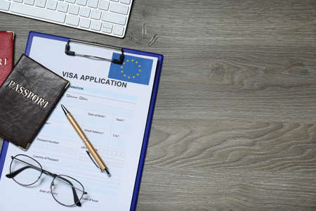 Visa application form for immigration to European Union, passports and glasses on wooden table, flat lay. Space for textの写真素材