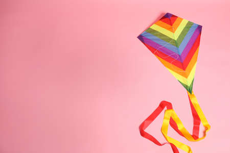 Bright rainbow kite on pink background, top view. Space for text