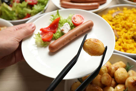 Woman taking food from buffet table, closeupの写真素材