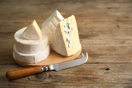 Different types of cheese and knife on wooden table