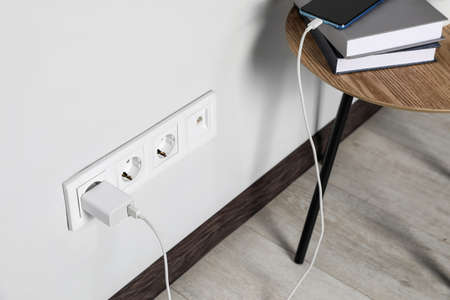Modern smartphone charging from electric socket indoors