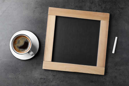 Clean small blackboard, chalk and cup of coffee on gray table, flat layの写真素材