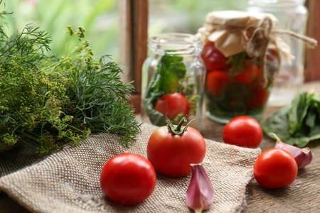 Glass jars, fresh vegetables and herbs on wooden table indoors. pickling recipeの写真素材