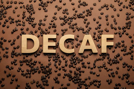 Word Decaf made of wooden letters on brown background with coffee beans, flat layの写真素材