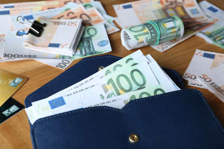 Wallet with different Euro banknotes and credit cards on wooden table, closeup. money exchangeの写真素材