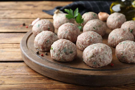 Many fresh raw meatballs on wooden tableの写真素材