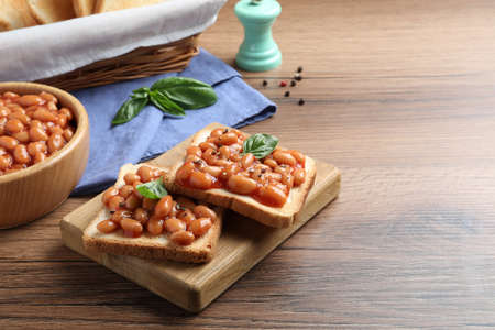 Toasts with delicious canned beans on wooden table, space for textの写真素材