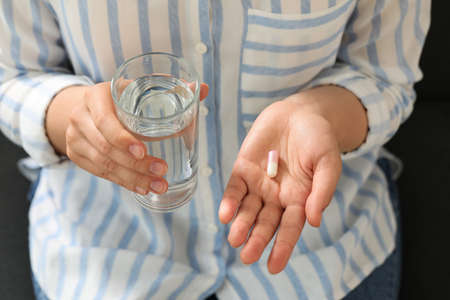 Young woman with dietary pill and glass of water, above view