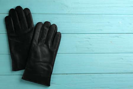 Stylish black leather gloves on turquoise wooden background, flat lay. Space for textの写真素材