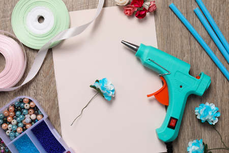 Hot glue gun and handicraft materials on wooden table, flat layの写真素材