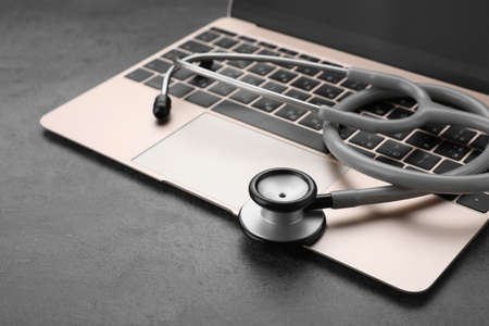 Laptop with stethoscope on gray table, closeup. Space for textの写真素材