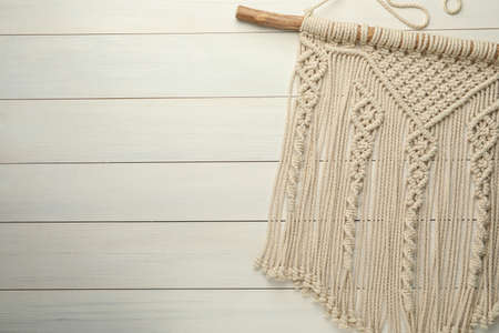 Stylish beige macrame on white wooden table, top view. Space for text