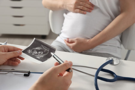 Pregnant woman having appointment in hospital, focus on doctor with ultrasound scan