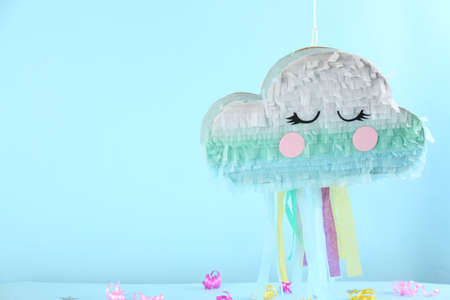Cloud shaped pinata hanging on light blue background. Space for textの写真素材