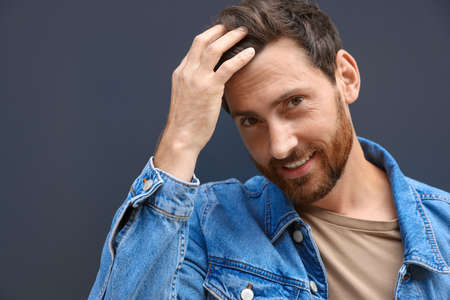 Portrait of smiling handsome bearded man on gray background. Space for text