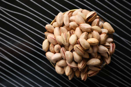Many tasty pistachios on black table, top view