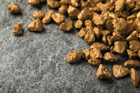 Pile of gold nuggets on gray table, space for text