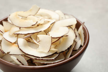 Tasty coconut chips in ceramic bowl, closeup