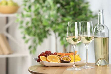 Delicious exotic fruits and wine on wooden table indoors, space for textの写真素材