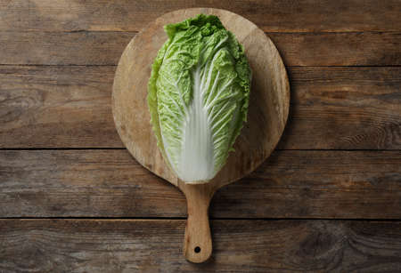 Cutting board with fresh ripe Chinese cabbage on wooden table, top viewの写真素材