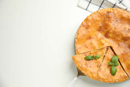 Delicious pie with meat and basil on white table, flat lay. Space for text