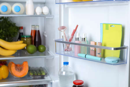 Storage of cosmetics in refrigerator door bin next to groceriesの写真素材
