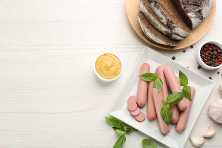 Fresh raw vegetarian sausages with basil, garlic and sauce on white wooden table, flat lay. Space for textの写真素材