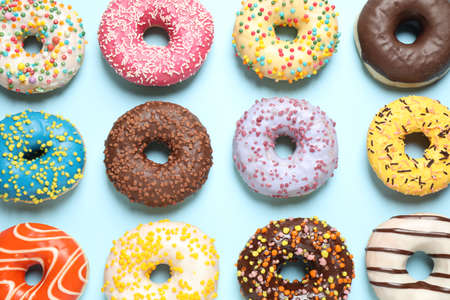 Delicious glazed donuts on light blue background, flat layの写真素材