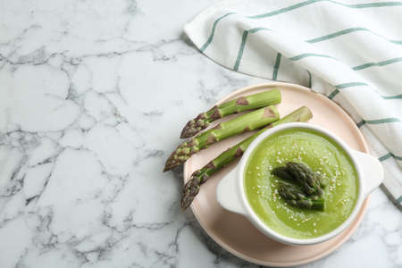 Delicious asparagus soup served on white marble table, flat lay. Space for textの写真素材