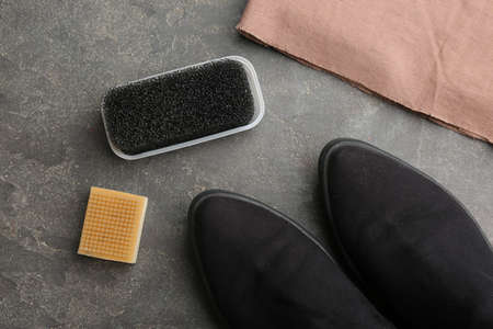 Stylish footwear with shoe care accessories on gray stone table, flat lay
