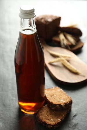 Bottle of delicious fresh kvass, spikelets and bread on gray table, closeup