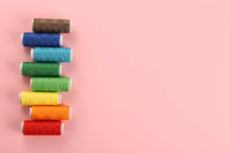 Different colorful sewing threads on pink background, flat lay. Space for textの写真素材