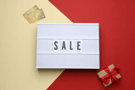 Lightbox with word Sale, gift box and credit cards on color background, flat layの写真素材