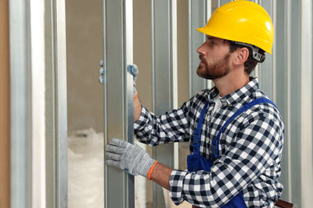 Professional builder in uniform working with metal bars indoors