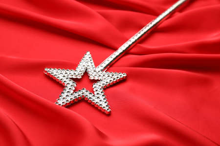 Beautiful silver magic wand on red fabric, closeup