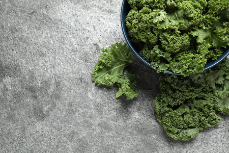 Fresh kale leaves on gray table, flat lay. Space for text