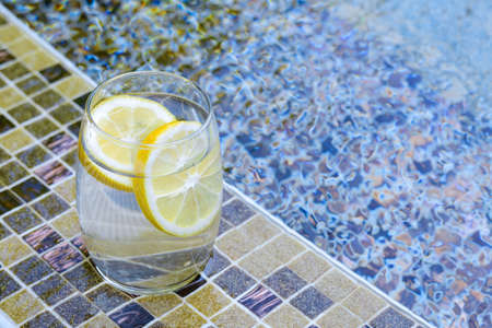 Refreshing water with lemon on edge of swimming pool, space for textの写真素材
