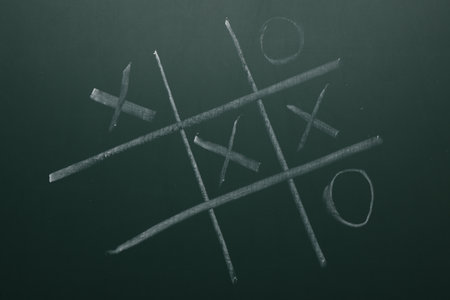 Tic tac toe game on green chalkboard, top viewの写真素材
