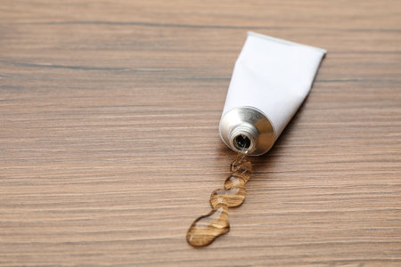 Open white tube with ointment on wooden table. Space for text