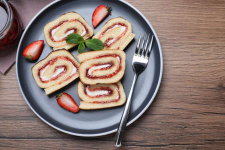 Tasty cake roll with strawberry jam and cream on wooden table, flat layの写真素材