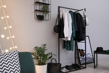 Rack with stylish women's clothes and shoes in dressing room