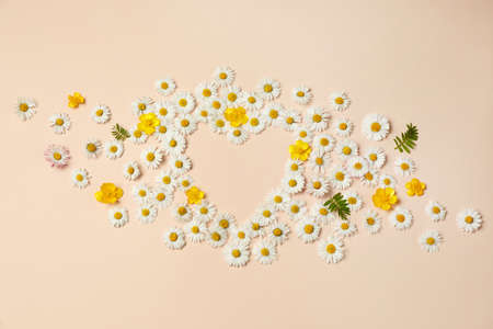 Heart shaped frame of beautiful flowers on beige background, flat lay. Space for textの写真素材