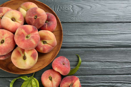 Fresh ripe donut peaches on gray wooden table, flat lay. Space for textの写真素材