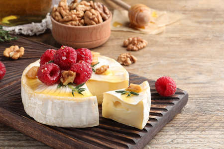 Brie cheese served with raspberries, walnuts and honey on wooden table. Space for textの写真素材