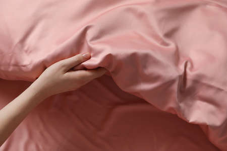 Woman making bed with beautiful pink silk linens, closeup viewの写真素材
