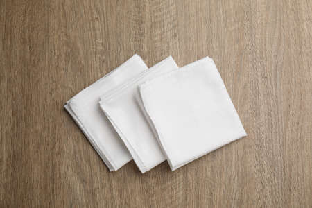 Stylish white handkerchiefs on wooden table, flat lay